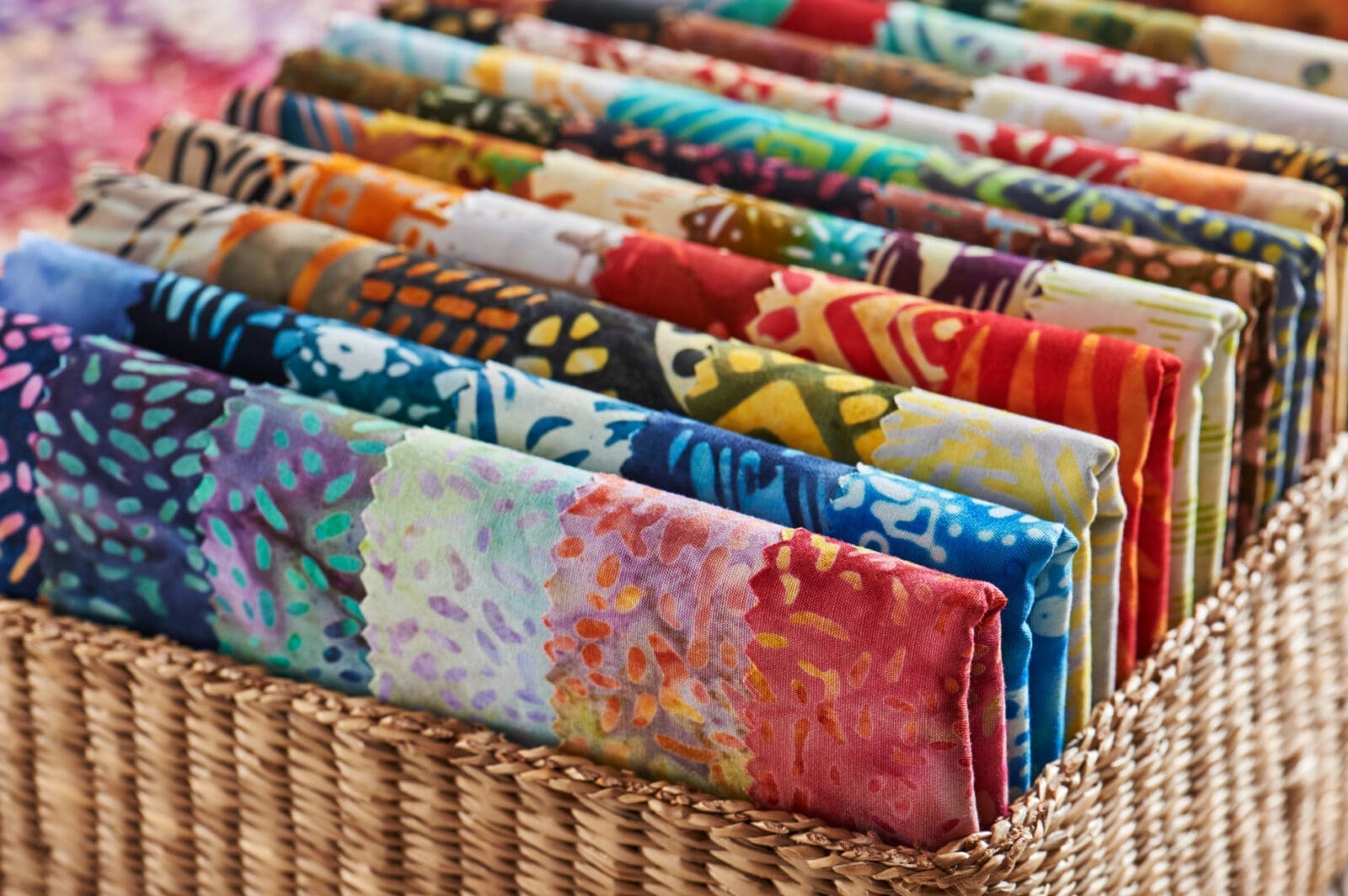 Folded bright pieces of quilting batik fabrics in a basket, macro